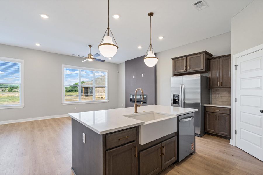 Kitchen island featuring a white farmhouse sink, brass faucet, and white countertop