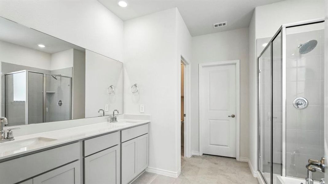 Contemporary bathroom featuring a double vanity with light gray cabinetry, a spacious framed glass shower, and large format floor tiling