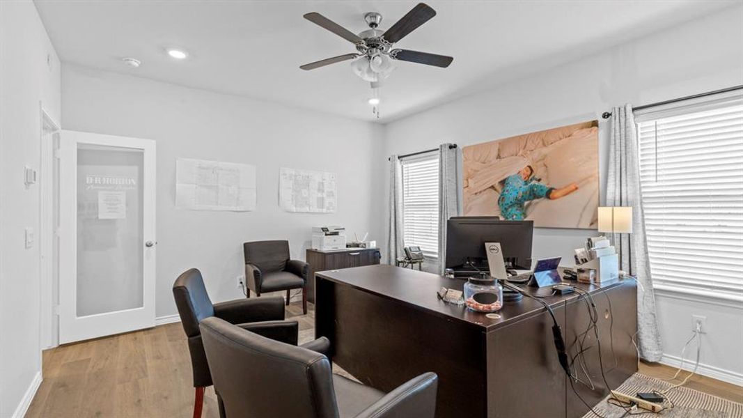 Light-filled room featuring wood-finish flooring, two windows with blinds, recessed lighting, and a ceiling fan Light-filled room featuring wood-finish flooring, two windows with blinds, recessed lighting, and a ceiling fan