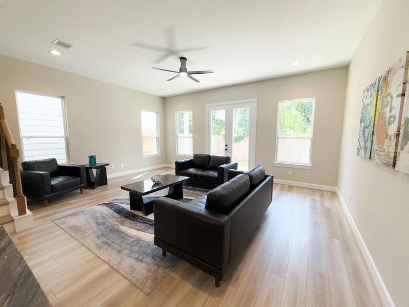 The ROCburne’s living room offers a wall of windows framing the backyard, filling the space with natural light and creating a seamless connection to outdoor living. Image depicts home as-is.