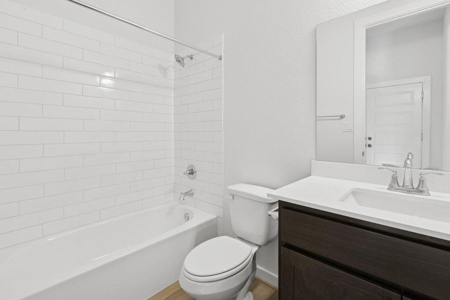 Bathroom with bathtub / shower combination, vanity, and a textured wall Bathroom with bathtub / shower combination, vanity, and a textured wall