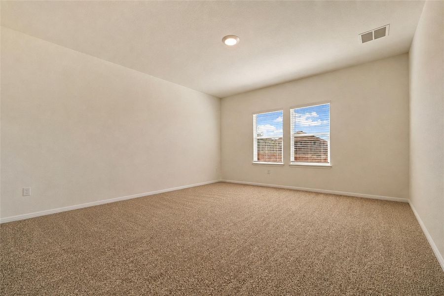 Primary bedroom, featuring recessed lighting, soft carpet flooring and abundant natural light.
