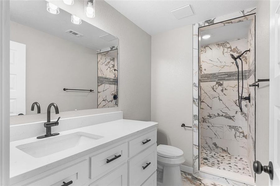 Primary bathroom with light marble finish floors, vanity, and a marble finish shower