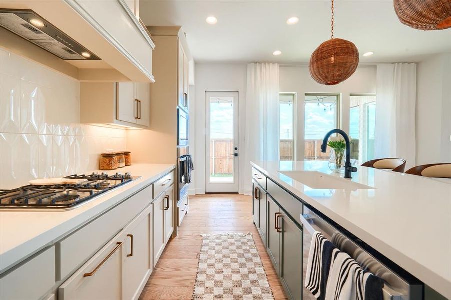 Kitchen with custom exhaust hood, decorative backsplash, white cabinetry, light hardwood / wood-style floors, and sink