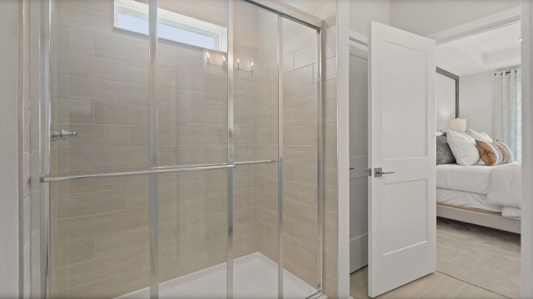 Glass walk-in shower with tile in the owner’s suite of the Jupiter Model by DRB Homes at Grasslands West in Lakeland, FL.