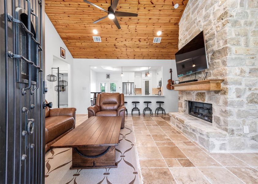 The spacious living area features soaring wood-accented ceilings, a striking stone fireplace, and an open-concept layout that flows seamlessly into the kitchen and dining area. Warm finishes and comfortable seating create the perfect space for relaxing or entertaining.