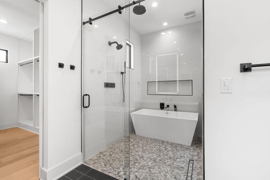 A well-appointed bath features a spacious glass-enclosed shower with an adjacent freestanding soaking tub.