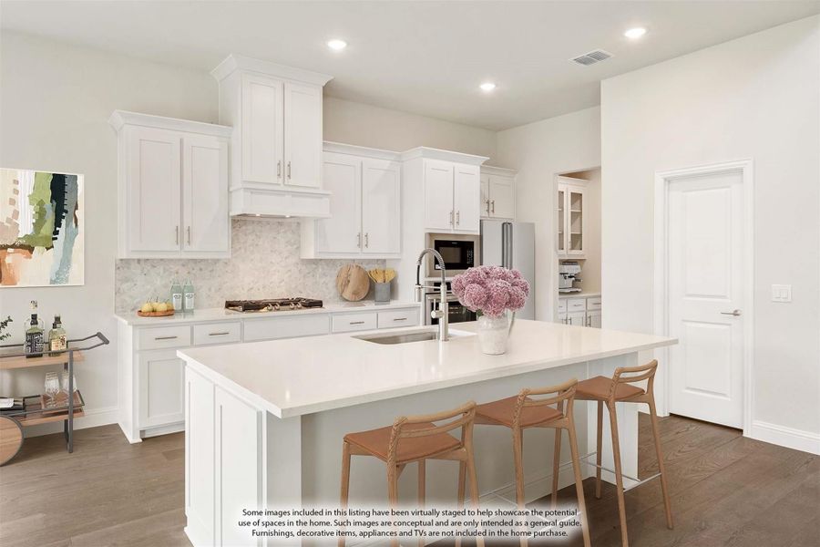 Kitchen with white cabinets, large island with seating, tile backsplash, and stainless steel appliances on hardwood floors