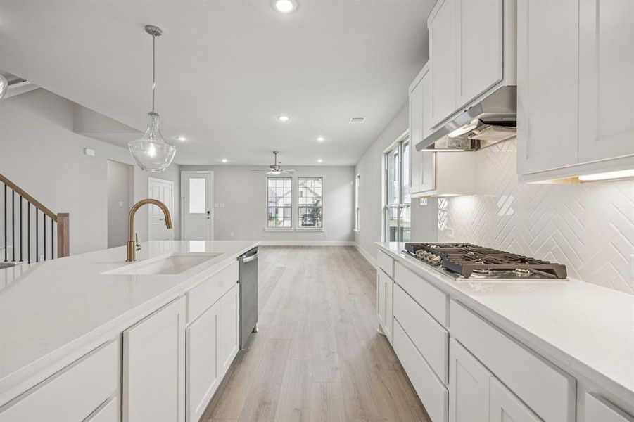 Kitchen featuring white cabinetry, pendant lighting, recessed lighting, light wood-style flooring, and light stone counters Kitchen featuring white cabinetry, pendant lighting, recessed lighting, light wood-style flooring, and light stone counters