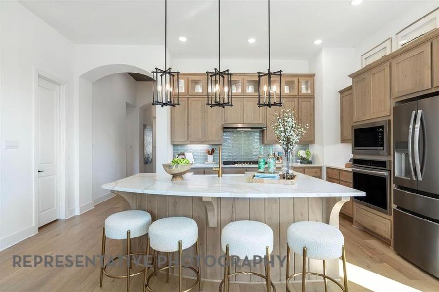 Kitchen with backsplash, appliances with stainless steel finishes, light wood-style floors, a spacious island, and recessed lighting