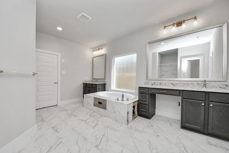 Elevate your daily routine at the elegant vanity, now equipped with double sinks, light countertops, modern hardware, and beautiful vanity lights.