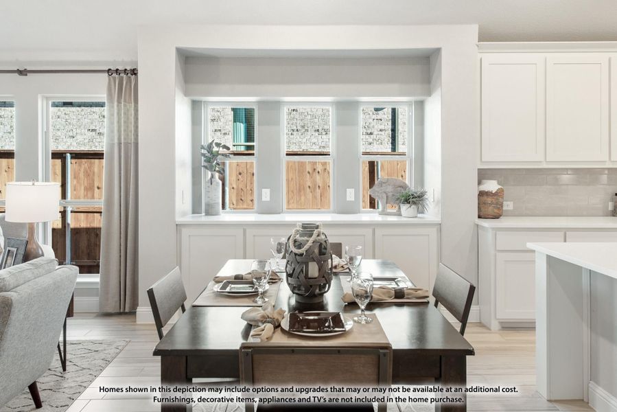 Dining area with dark wood table, set for four, beside open kitchen with white cabinets and light wood floors