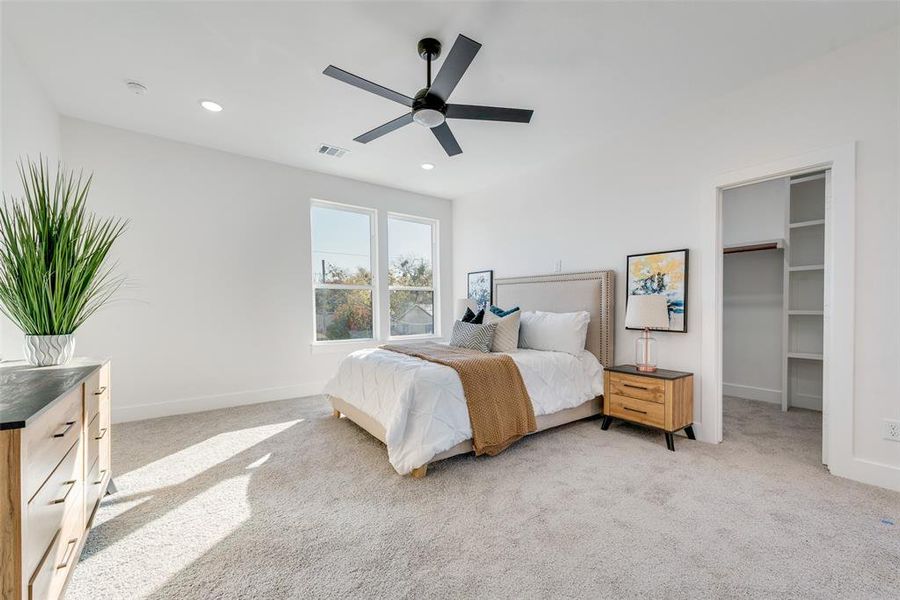 Bedroom featuring light carpet, a walk in closet, and ceiling fan