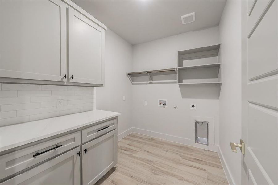 Laundry room with gas dryer hookup, light wood-style flooring, hookup for a washing machine, cabinet space, and hookup for an electric dryer