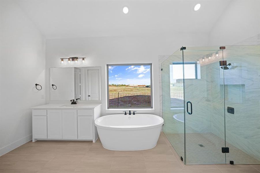 Bathroom with a freestanding tub, a marble finish shower, vanity, recessed lighting, and light tile patterned floors