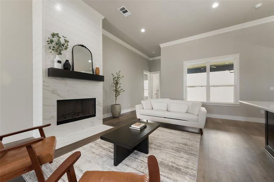 Living room with a high end fireplace, ornamental molding, and hardwood / wood-style flooring