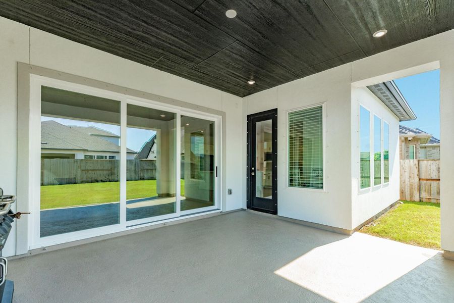 Spacious open-concept living area featuring seamless indoor-outdoor flow through triple glass doors that connect the kitchen and family room directly to the patio.