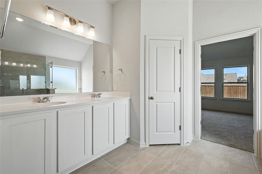 Full bath with double vanity, light tile patterned floors, walk in shower, and lofted ceiling Full bath with double vanity, light tile patterned floors, walk in shower, and lofted ceiling