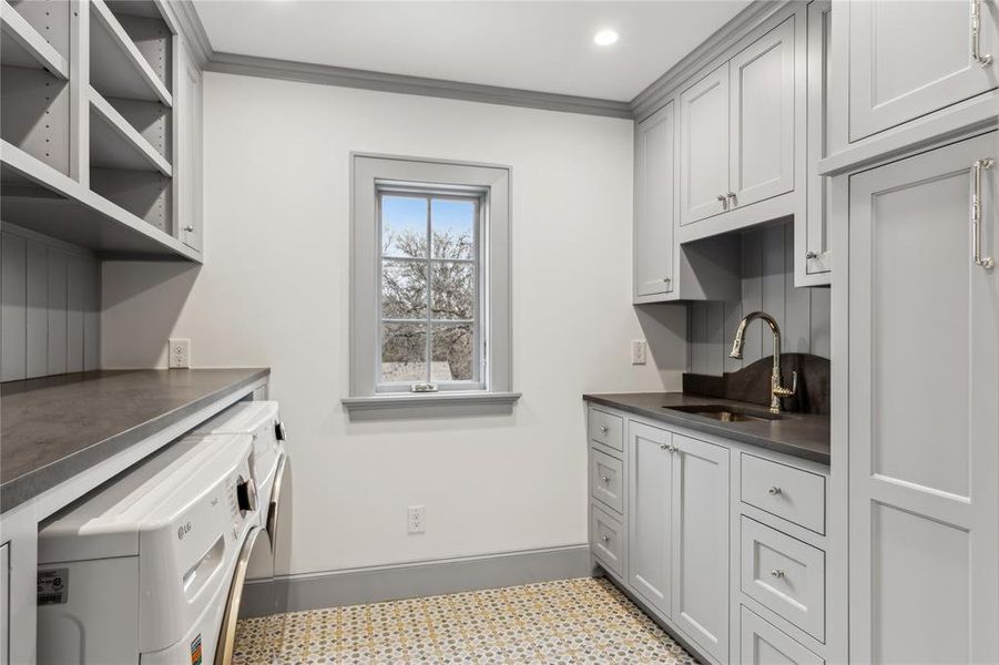 Kitchen with dark countertops, crown molding, separate washer and dryer, and a sink