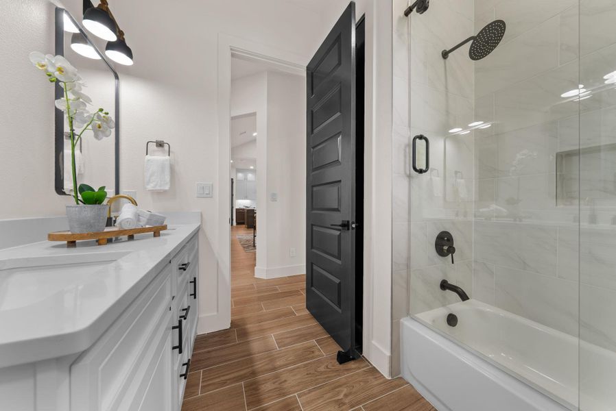 White countertops and rich wood-toned tile flooring adorn this modern bathroom.