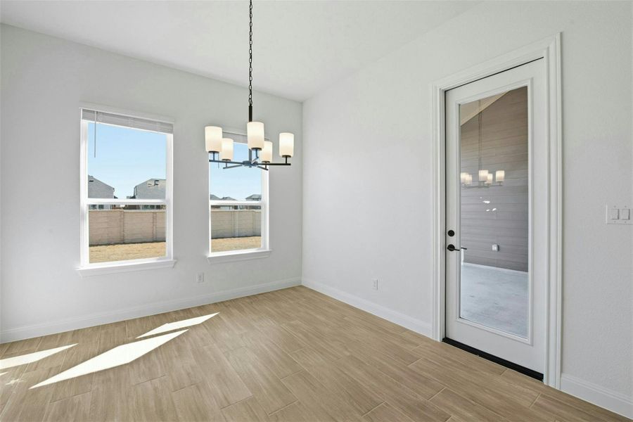 Unfurnished dining area with hanging lights and wood tiled floors