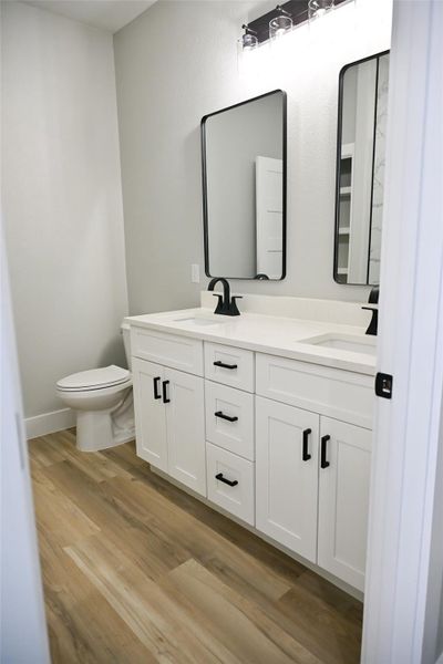 Full bath featuring double vanity and light wood-style floors