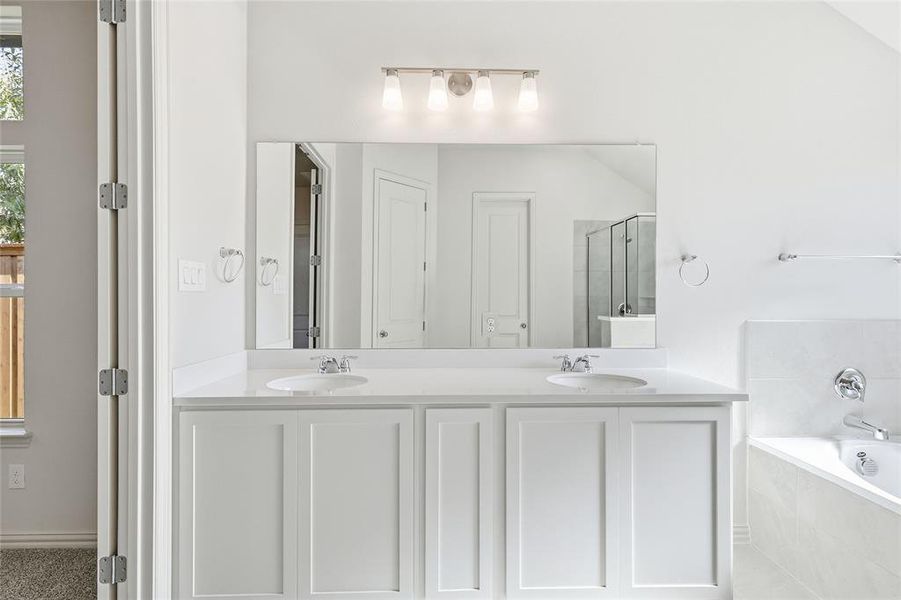 Full bath with a bath, double vanity, and a stall shower