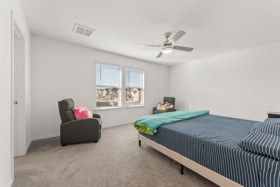 Bedroom featuring light carpet, ceiling fan, visible vents, and baseboards