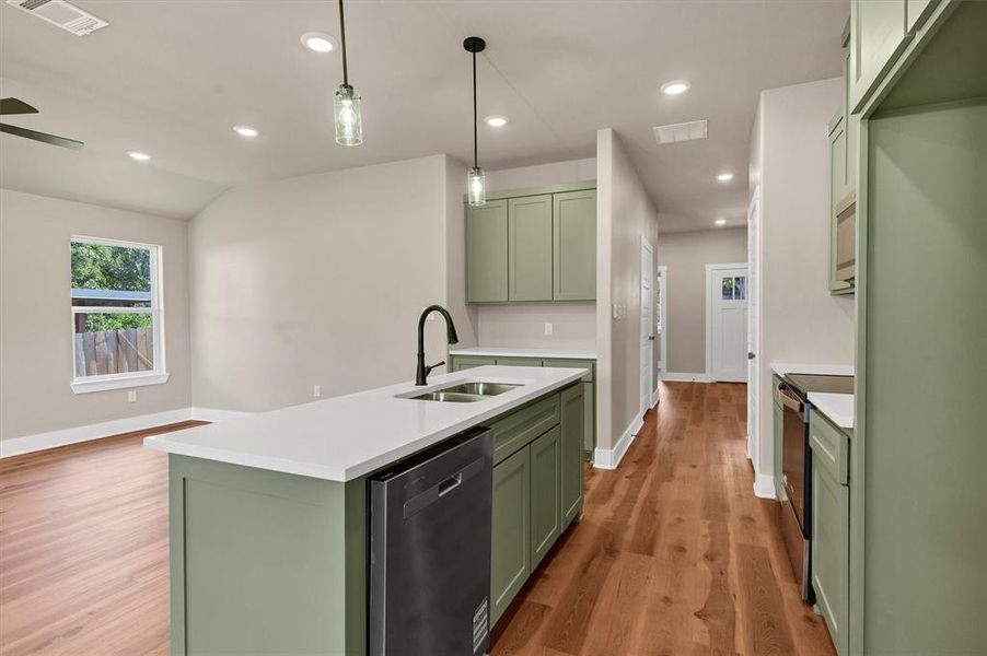 Kitchen with green cabinetry, appliances with stainless steel finishes, light wood-style flooring, recessed lighting, and an island with sink Kitchen with green cabinetry, appliances with stainless steel finishes, light wood-style flooring, recessed lighting, and an island with sink