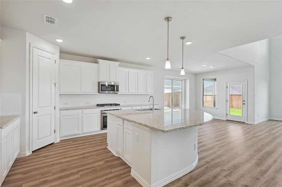 Kitchen featuring appliances with stainless steel finishes, light hardwood / wood-style flooring, white cabinets, and backsplash