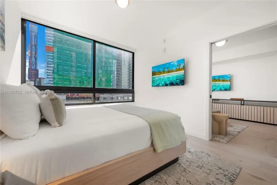 Floor-to-ceiling windows with dark frames, wood-finish flooring, and minimalist white walls Floor-to-ceiling windows with dark frames, wood-finish flooring, and minimalist white walls