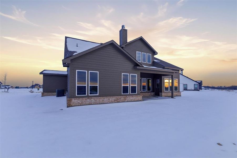 Snow covered house with a patio area and a chimney
