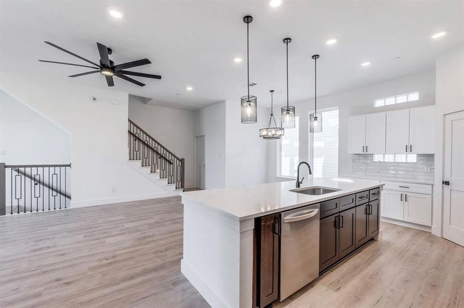 Kitchen featuring decorative light fixtures, dishwasher, light hardwood / wood-style floors, white cabinetry, and ceiling fan