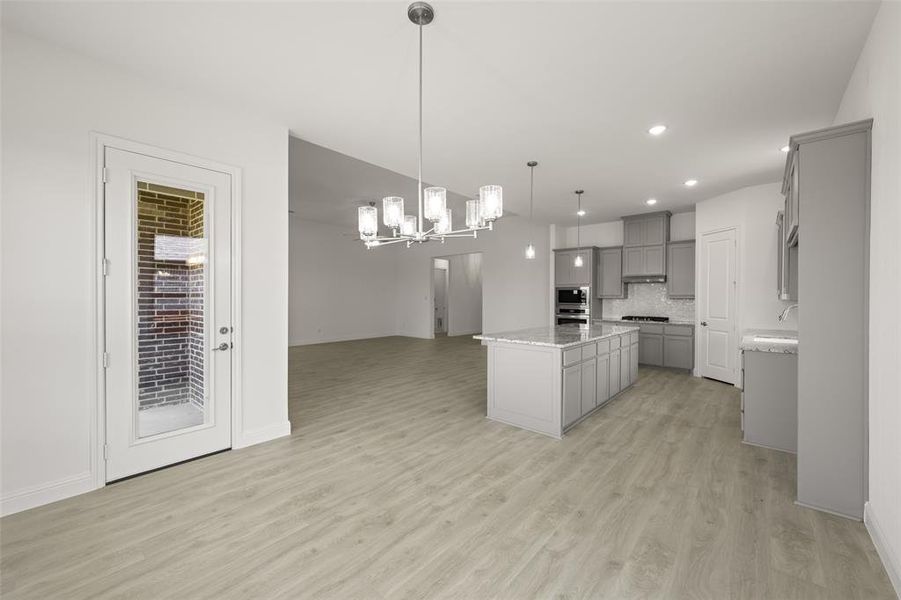 Kitchen with gray cabinets, a chandelier, a kitchen island, light wood-style flooring, and recessed lighting Kitchen with gray cabinets, a chandelier, a kitchen island, light wood-style flooring, and recessed lighting
