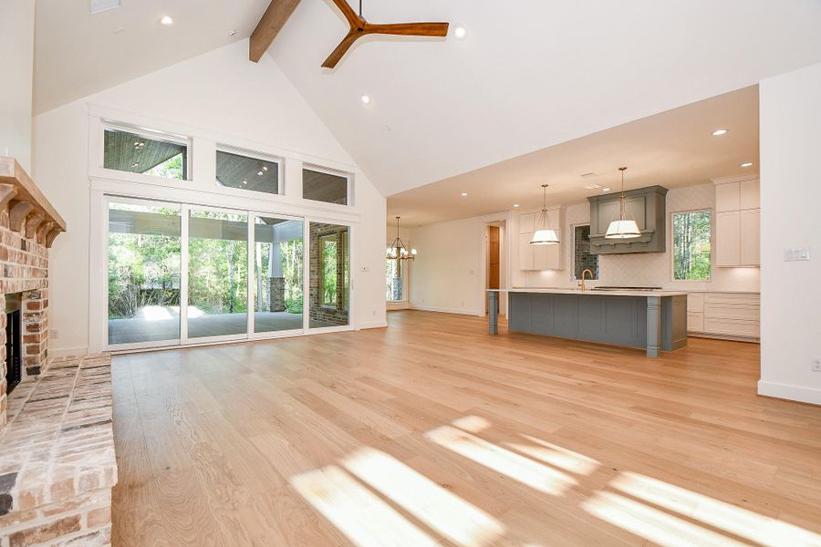 The heart of the home features soaring ceilings with exposed wood beams, wide-plank hardwood floors, and a cozy brick fireplace. Wall-to-wall glass doors seamlessly connect the indoor living space with the covered outdoor patio, bringing in serene wooded views and abundant light. The heart of the home features soaring ceilings with exposed wood beams, wide-plank hardwood floors, and a cozy brick fireplace. Wall-to-wall glass doors seamlessly connect the indoor living space with the covered outdoor patio, bringing in serene wooded views and abundant light.