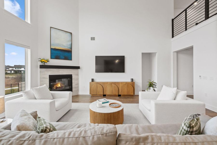 Living room featuring a towering ceiling, a glass covered fireplace, an abundance of natural light, and tiled floors