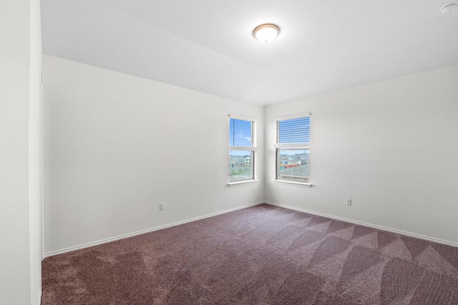 Room featuring two windows with blinds, neutral wall paint, and patterned carpet flooring