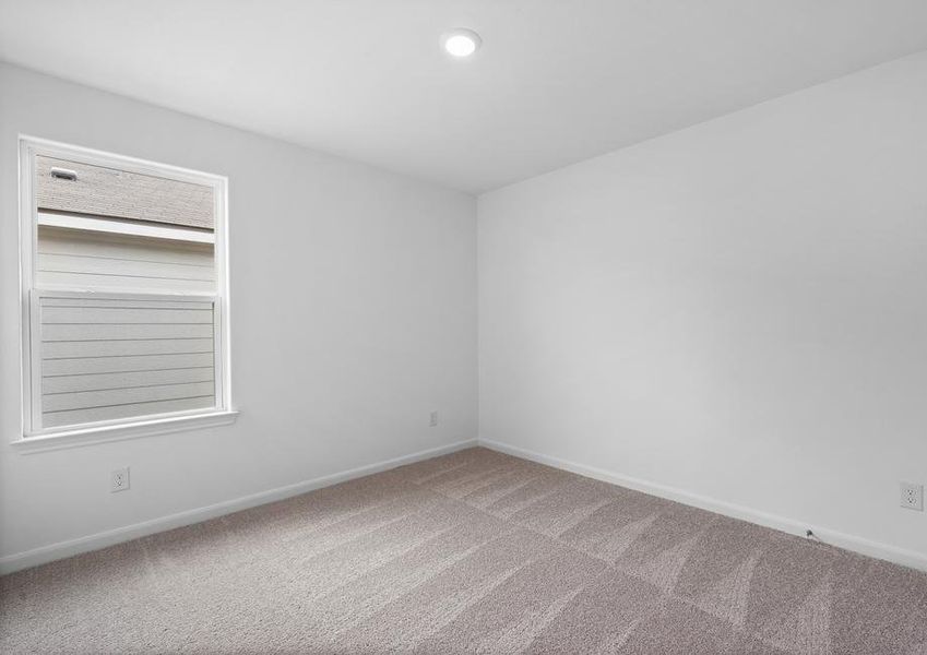 Secondary bedroom with a single window and tan carpet.