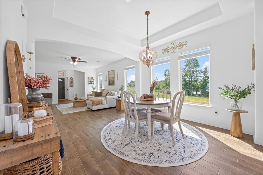 This inviting living and dining area features an open floor plan with abundant natural light streaming through large windows. The space is elegantly decorated with modern farmhouse accents, wood flooring, and a cozy seating arrangement. The dining area is highlighted by a stylish chandelier and round rug, offering a warm, welcoming ambiance. This inviting living and dining area features an open floor plan with abundant natural light streaming through large windows. The space is elegantly decorated with modern farmhouse accents, wood flooring, and a cozy seating arrangement. The dining area is highlighted by a stylish chandelier and round rug, offering a warm, welcoming ambiance.