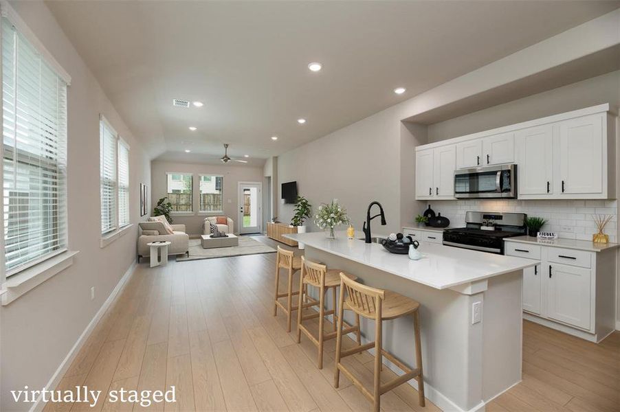 Kitchen featuring recessed lighting, open floor plan, gas stove, decorative backsplash, and a kitchen breakfast bar Kitchen featuring recessed lighting, open floor plan, gas stove, decorative backsplash, and a kitchen breakfast bar