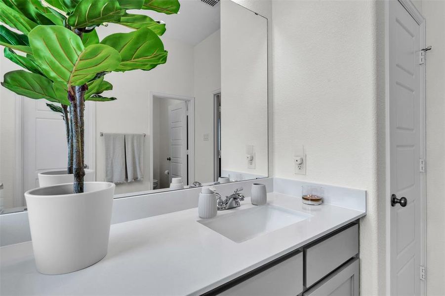Bathroom vanity with a white countertop featuring an integrated sink and chrome faucet Bathroom vanity with a white countertop featuring an integrated sink and chrome faucet