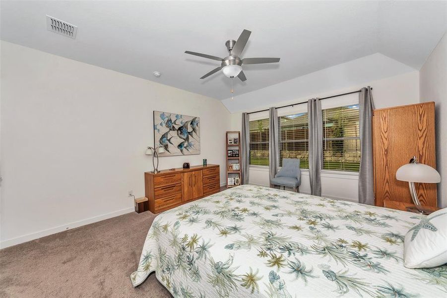 Bedroom with ceiling fan, carpet floors, and lofted ceiling