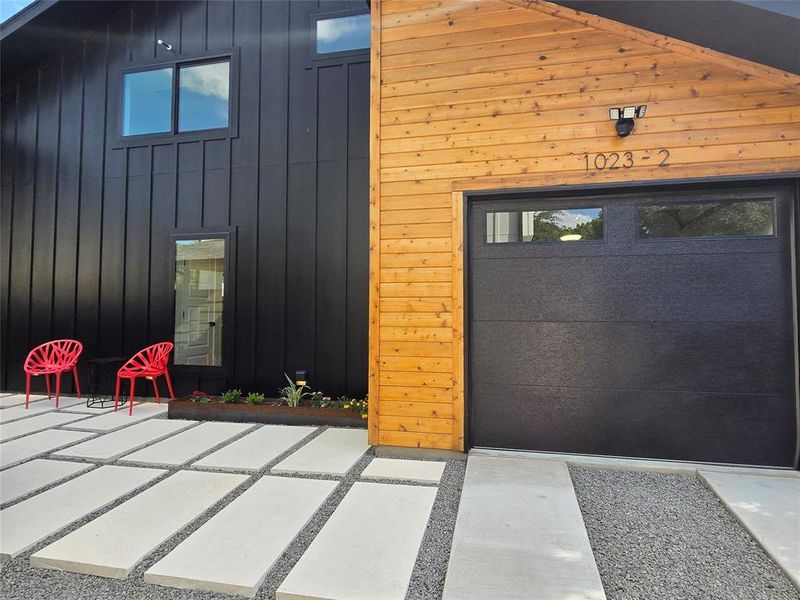 Custom large paver stone landscaping leading up to front door with metal planter boxes that provide just enough greenery. Drip irrigation in the planter boxes.