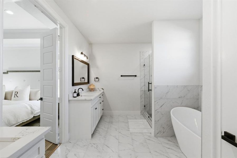 Ensuite bathroom featuring vanity, a freestanding bath, a marble finish shower, and light marble finish flooring
