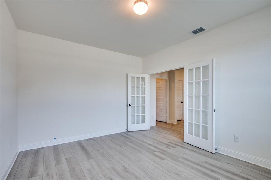 Unfurnished room with french doors and light wood finished floors Unfurnished room with french doors and light wood finished floors