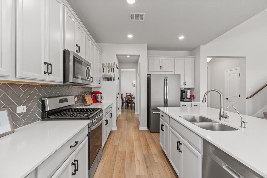 The kitchen is a chef's dream with a large center island, silestone countertops, a five burner gas cooktop, stainless steel appliances and ample space.