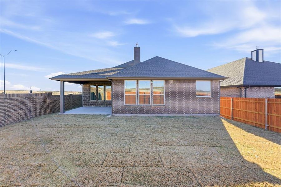 Back of house featuring a chimney, a patio, a fenced backyard, and brick siding