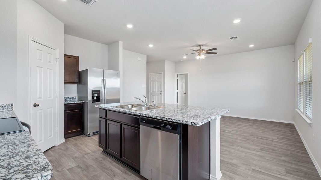 Kitchen featuring appliances with stainless steel finishes, recessed lighting, light wood-style floors, an island with sink, and dark brown cabinets