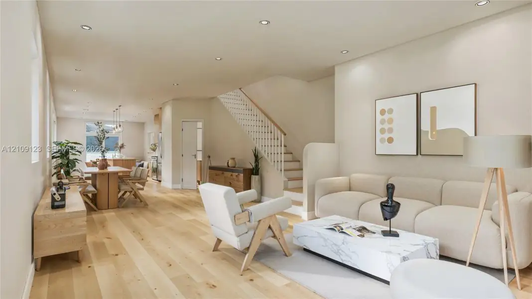 Open-concept floor plan featuring wood-finish flooring, recessed lighting, and a staircase with a wooden handrail and white balusters Open-concept floor plan featuring wood-finish flooring, recessed lighting, and a staircase with a wooden handrail and white balusters