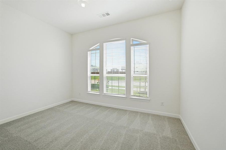 Carpeted interior room featuring a large arched window with horizontal blinds, white baseboard trim, and a ceiling-mounted light fixture